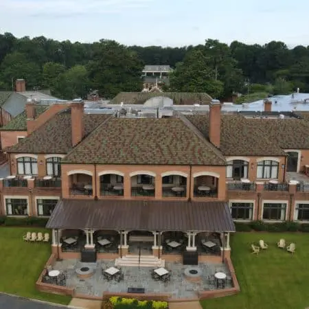 Aerial photo of upscale clubhouse with clean tile roof, open balconies, manicured lawn, and elegant outdoor seating after commercial roof cleaning service