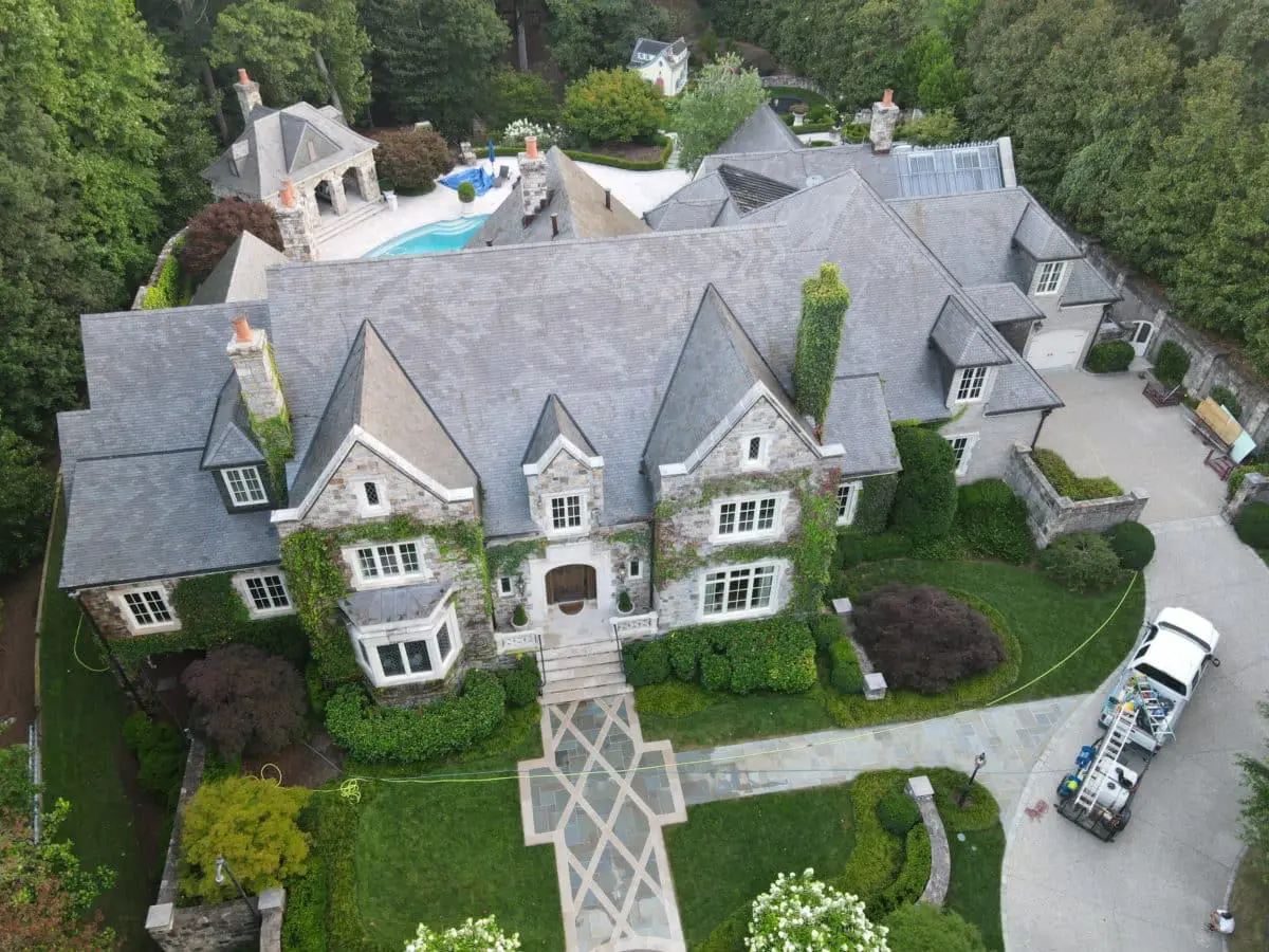 Aerial view of commercial roof cleaning using soft wash to remove algae and stains, enhancing energy efficiency and extending roof lifespan