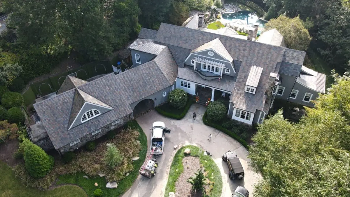 Algae on Roof – Causes & Prevention | Aqua-Nomics Aerial view of a home showing algae growth on roof shingles. Learn what causes algae on roofs and how professional cleaning helps maintain curb appeal and value