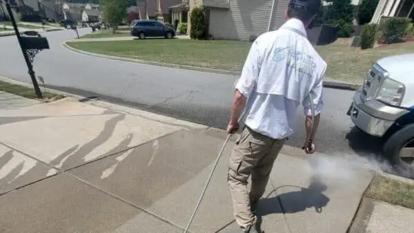 Professional cleaning of a concrete driveway using a pressure washer to remove stains, grime, and dirt buildup from your home’s exterior surfaces