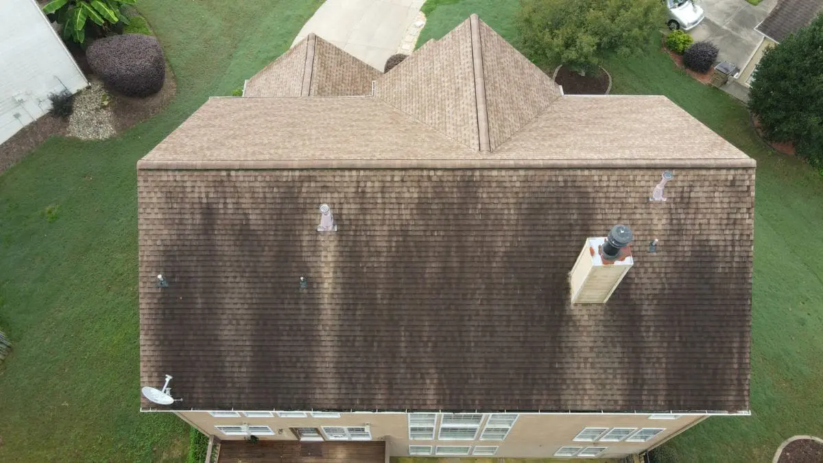 Aerial view of a roof with dark streaks from algae buildup highlights the need for seasonal roof cleaning to maintain curb appeal and prevent damage
