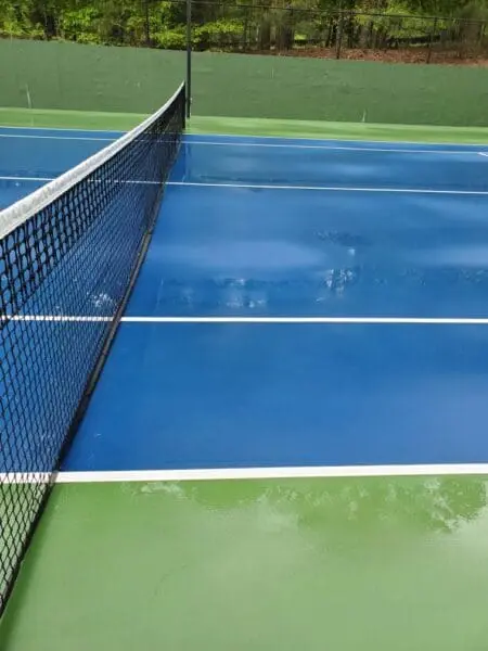 Pristine Tennis Court After Power Washing Close-up of a clean tennis court surface in Alpharetta, GA, highlighting the bright blue and green finish after HOA pressure washing service by Aqua-Nomics