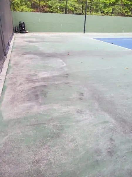 Tennis Court Surface Before Cleaning Dirty and stained tennis court surface showing grime and debris before Aqua-Nomics professional cleaning service