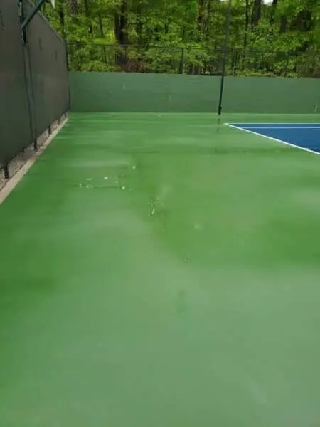 Clean HOA Tennis Court Surface in Alpharetta Freshly cleaned tennis court for an HOA in Alpharetta shows spotless green surface and sharp court lines after expert pressure washing by Aqua-Nomics