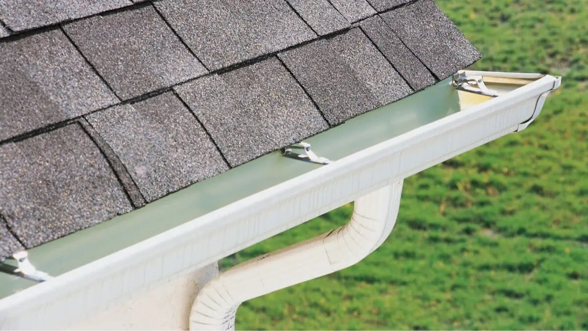 Close-up of clean roof gutters on a shingle roof. Learn the best times to schedule gutter cleaning to protect your home from seasonal debris and water damage