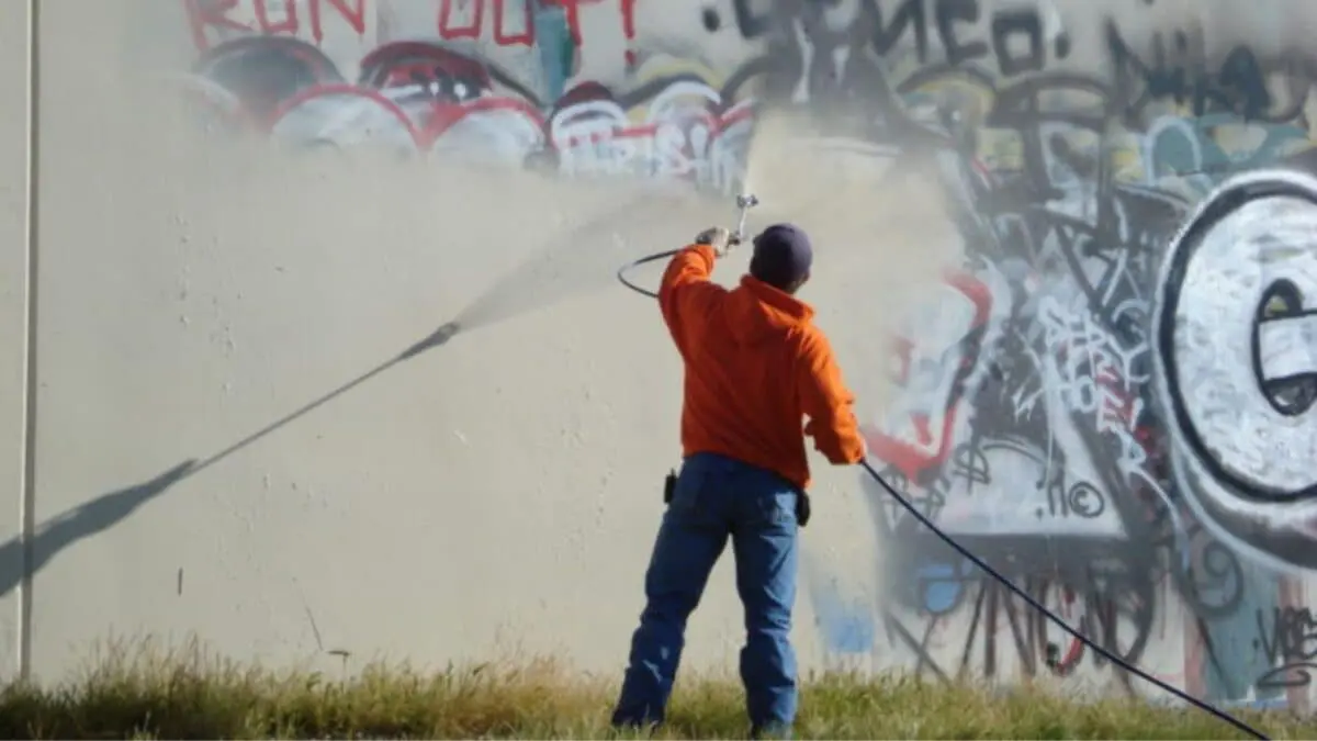 A technician power washes graffiti off a wall using high-pressure equipment. Learn expert tips on safe and effective graffiti removal with pressure washing