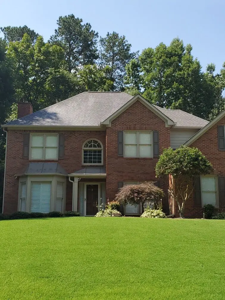 Freshly cleaned roof on a brick home enhances curb appeal and protects against algae and grime buildup for long-lasting beauty and performance
