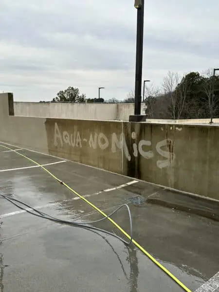 Dramatic contrast on a parking garage wall showcases the power of professional pressure washing in removing deep grime and restoring original surfaces