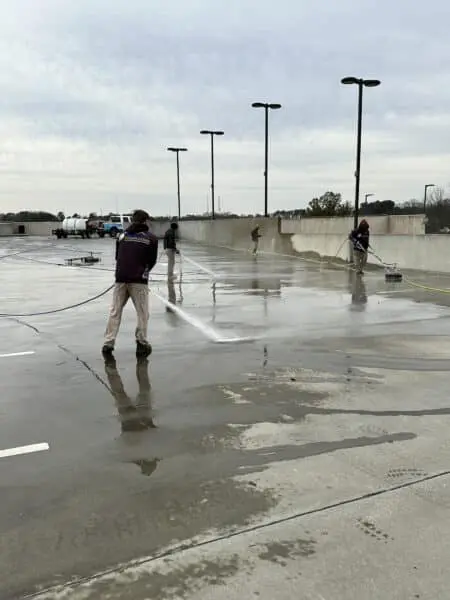 Professional crew restoring cleanliness and safety to parking decks using advanced pressure washing for stain removal and long-lasting surface results