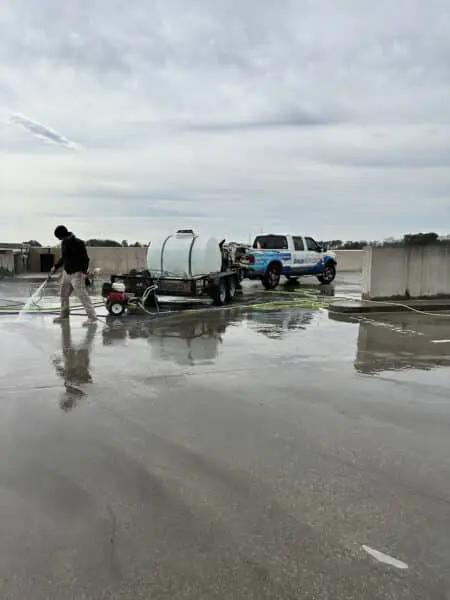 An Aqua-Nomics technician uses industrial equipment to pressure wash a parking deck, improving cleanliness and maintaining professional property standards