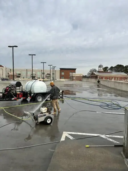A professional cleans a parking lot with pressure washing equipment in Alpharetta to enhance surface safety and improve property appearance