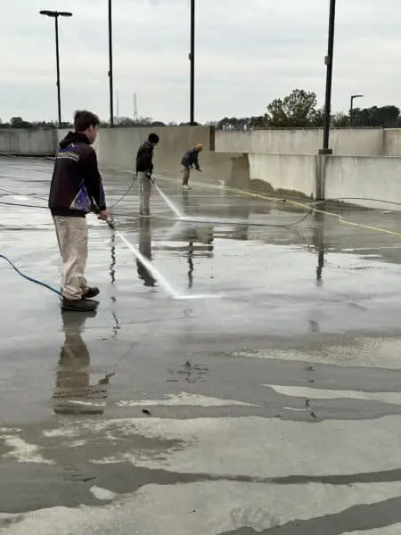 Professional crew using high-pressure equipment to clean commercial parking garage walls and floors, enhancing safety, appearance and cleanliness