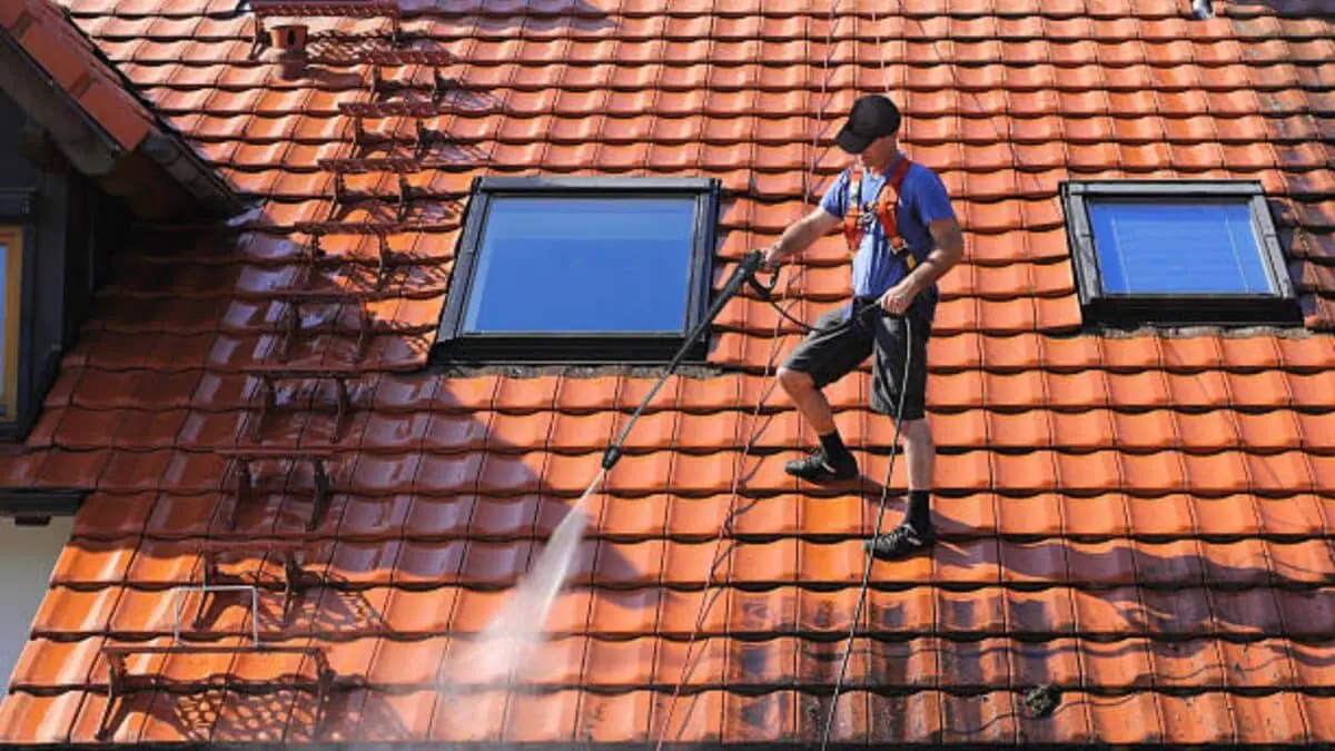 Technician safely prepares red tile roof for pressure washing, ensuring optimal cleaning results with Aqua-Nomics expert roof maintenance service