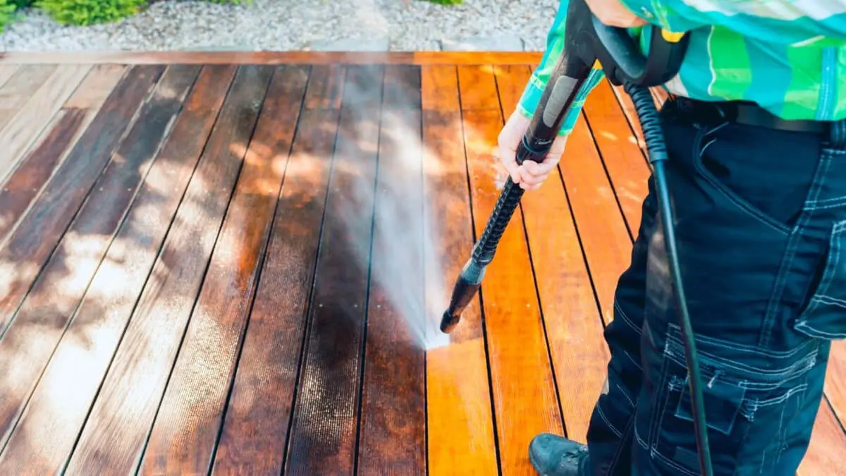 Close-up of power washing removing dirt from a wooden deck using high-pressure water, demonstrating the efficiency of modern exterior cleaning technology