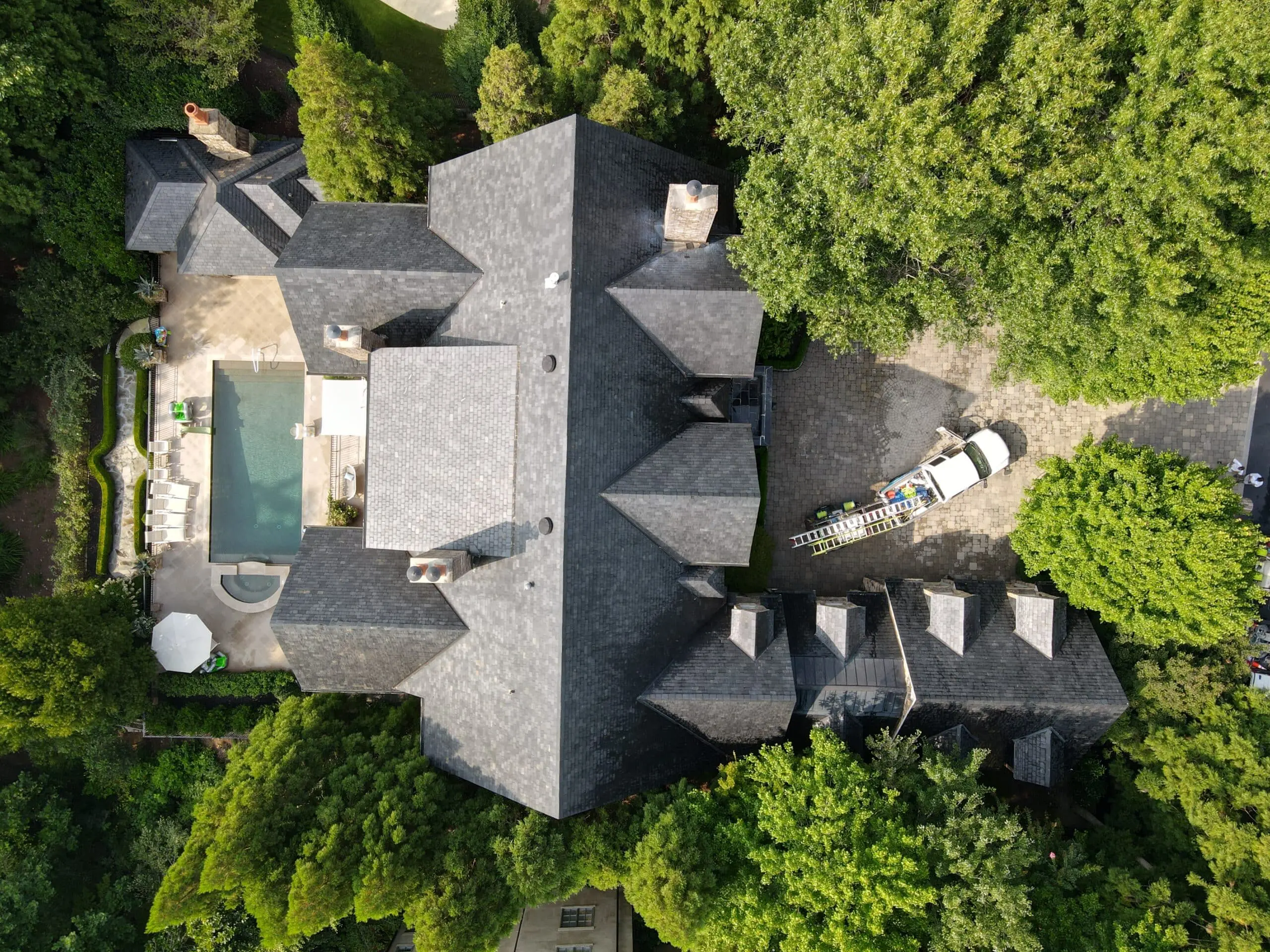 Aerial View of Clean Slate Roof and Pool Bird’s-eye view of estate with newly cleaned slate roof and pool area—Aqua-Nomics delivers top-tier residential roof cleaning results
