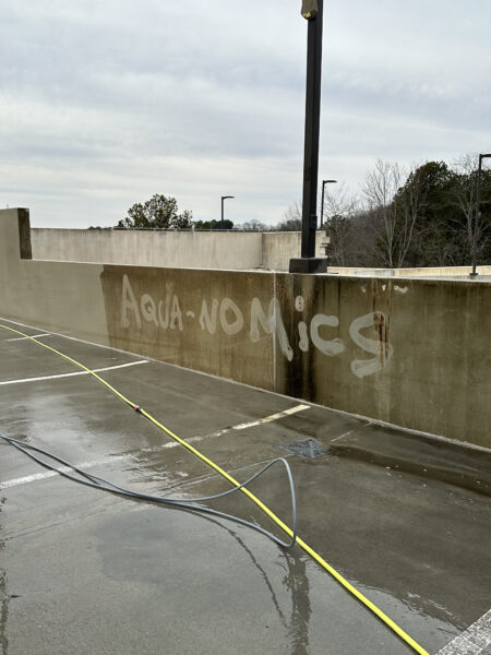 A Concrete Wall With A Yellow Hose And A Black Pole